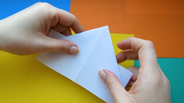 Step 4. female hands make paper boat. Step-by-step instructions on how to make origami paper ship.