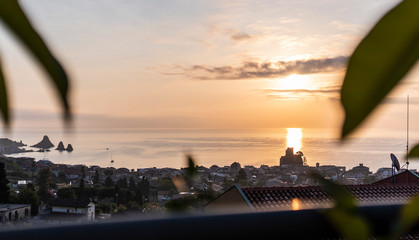 Landscape of the sunset of the Sicilian seashes, sea views with horizon and glimpse of the sunlit city, Faraglioni