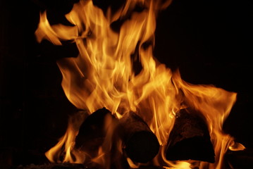 firewood burning in fireplace on dark background
