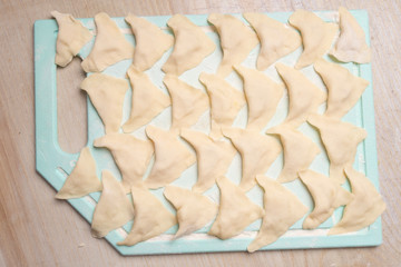 Dough dumplings with potatoes lie on a cutting board. Cooking at home.