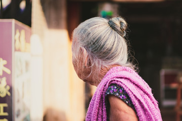 Old Japanese lady with white hear buying at the market.