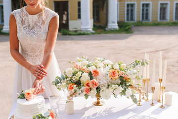 White wedding cake with flowers. Bride eat cake. Decorated table with flowers, served for two...