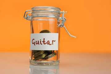 Guitar word on piggy Bank, moneybox, money jar with coins