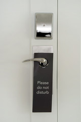 Do No Disturb sign at hotel room door. Do Not Disturb sign hang on door knob. Close-up.