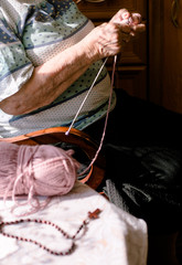 Polish grandmother still remember how to knit. Lilac crewel and rosary on the table. 