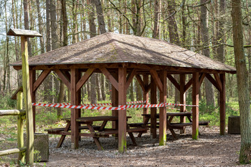 Fototapeta na wymiar A forest shelter secured with tape. Closed forest sheds during the COVID-19 quarantine. No entry to the forest.