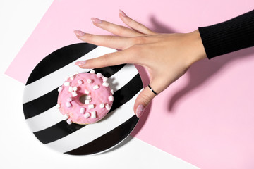 Female hand with trendy marble manicure holding donut