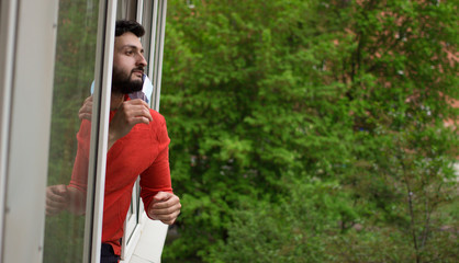 Quarantine is over concept. Man taking off medical mask looking out of window 