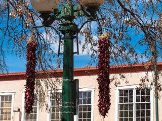 Traditional lamppost, two chile ristras, and an historic public building on the Plaza at Santa Fe,...