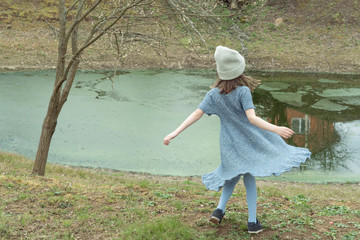 
Little girl in a woolen dress near a small lake in spring