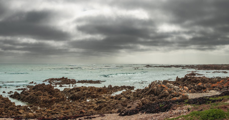 Cape Agulhas in South Africa with a rough coast and dark rain shower clouds
