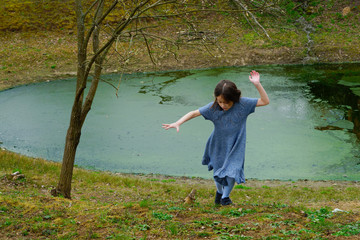 
Little girl in a woolen dress near a small lake in spring