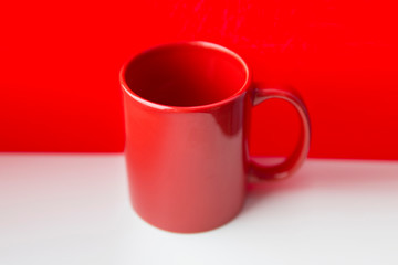 Red ceramic mug on a white and red background.