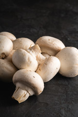 Champignon mushrooms healthy food on dark black textured background, macro