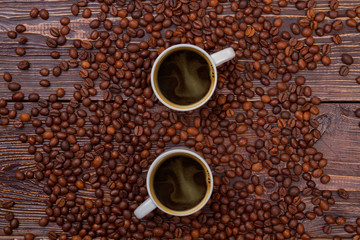 Cups of hot coffee and coffee beans. Top view flat lay. Brown wooden background.