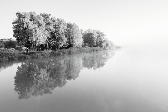River in morning fog. Autumn trees. Black white landscape