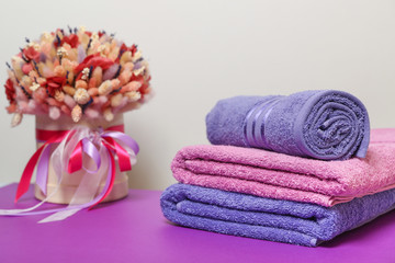 Obraz na płótnie Canvas folded towels and dry flower composition on purple table