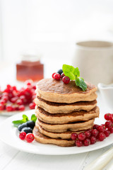 Stack of tasty pancakes topped with berries on white table. Breakfast food, fluffy american buttermilk pancakes