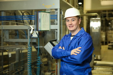 factory worker on the background of the equipment control panel at the factory. the factory engineer looks at camera