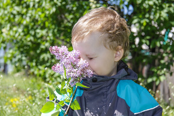 Boy with flowers. Sniffs the lilac.