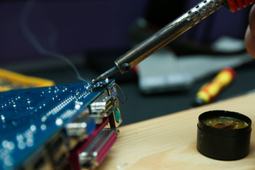 backdrop of smoking soldering iron and computer board on dark background. 