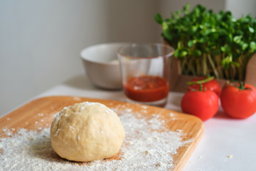 Preparing pizza dough. Wooden board in flour. Cooking homemade italian pizza. Preparation raw ingredients for baking. Fresh natural healthy food. Сulinary сhef kneading dough on kitchen table
