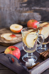 Warm soothing tea made from apples and cinnamon in glasses on a wooden table. Detox concept, antidepressant. Rustic style