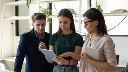 Serious businessman and businesswoman business talking looking at tablet screen. Confident woman leader and colleague discuss joint project development. Teamwork at workplace concept.