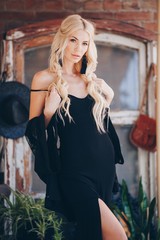Portrait of beautiful young blonde in the black clothing of style of бохо in a summer arbour