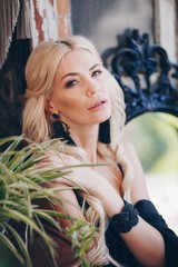 Portrait of beautiful young blonde in the black clothing of style of бохо in a summer arbour