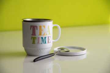 White cup of tea with slogan Tea time on a table with a green background