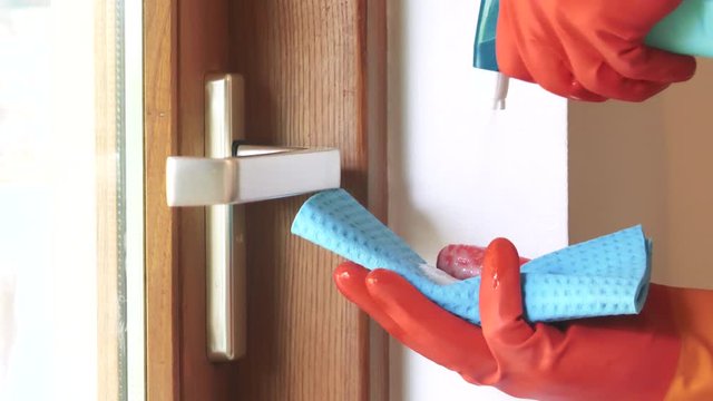 Nettoyage par d&eacute;sinfection du coronavirus en pulv&eacute;risant un antisepsie assainissent sur une poign&eacute;e de porte de placard m&eacute;tallique, muni de gant de protection.