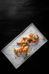 spicy fried shrimp skewers served on plate on black wooden table background
