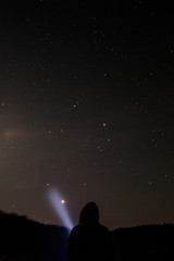 Fototapeta na wymiar Man shining a flashlight in the starry sky