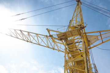 crane at a construction site. Against the background of blue sky and bright sun.