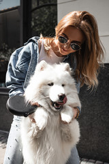 Beautiful girl with a  Cute  beautiful  Samoyed dog in a park  with owner outdoors