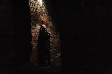 Young man standing near the wall in the abandoned buiding under light ray