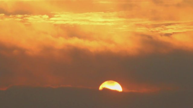 Time lapse of the rising sun with the sky full of clouds.