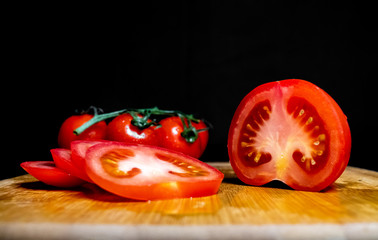 sliced tomatoes and cherry tomatoes are on the cutting Board. Ripe vegetables. Tomato set. Dark background. Healthy diet. Vegetarian food. Healthy diet. The design concept of the product.