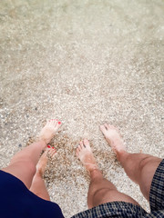 female legs with manicure and male legs in the water