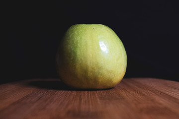 Green apple is lying on a wooden Board. Organic fruit. Healthy lifestyle. Sweet fruit. Vegetarian healthy food. Natural background. Dark background.