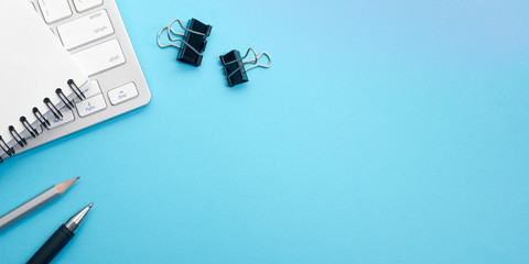 Blue desk office with laptop, smartphone and other work supplies with cup of coffee. Top view with...