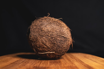 Coconut is lying on a wooden Board. Tasty tropical fruit. healthy nutrition. Diet concept. Concept design. Closeup of coconut. Healthy fresh nutrition. Vegetarian healthy food. Dark background.