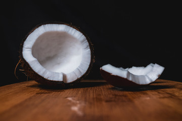 Split coconut is lying on a wooden Board. Tasty tropical fruit. healthy nutrition. Diet concept. Concept design. Closeup of coconut. Healthy fresh nutrition. Vegetarian healthy food. Dark background.