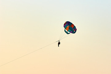 Silhouette of a Parasailers Flying On Colorful Parachute In colorful romantic sunset