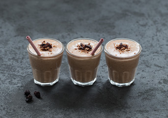 Smoothie from dried fruits and nuts  with granola in a glass with a bamboo tube on a dark background