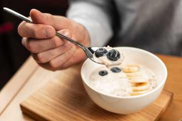 Plate with rice porridge on the table and a spoon in the hand.