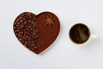 Mug of strong coffee and decorative heart. Coffee beans and instant coffee in a shape of heart isolated on white.