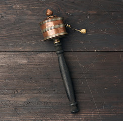 copper Tibetan prayer drum on a brown wooden background