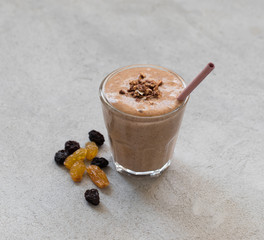 Smoothie of dried fruits, prunes, Golden and dark raisins in a glass with a bamboo tube on a light gray background